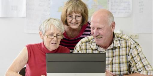Drei Senioren schauen zusammen in ein Tablet
