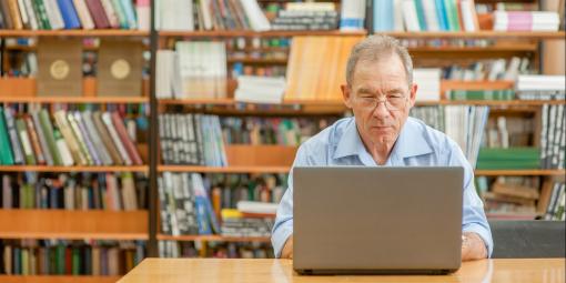 Mann mit Laptop in Bibliothek