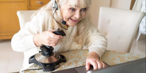 Frau sitzt mit Controller vor Laptop und spielt