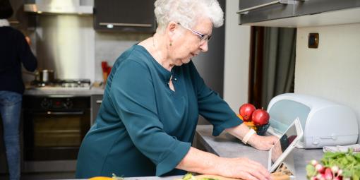 Frau mit Tablet kocht