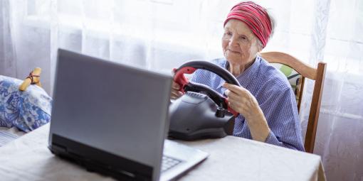Ältere spielt mit Lenkrad am PC