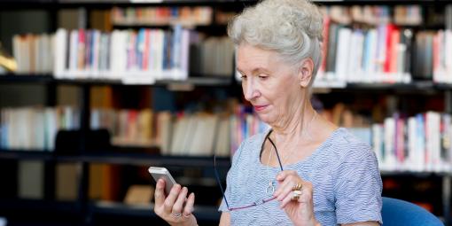 Ältere mit Smartphone in Bibliothek