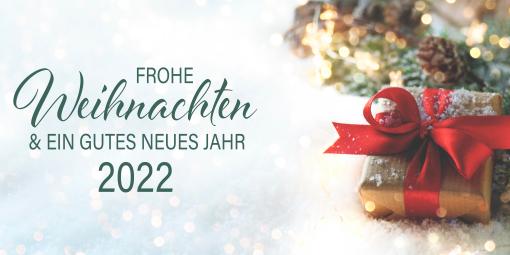 Weihnachtliche Grüße und ein gutes neues Jahr 2022. Daneben Tannenzweige und ein Geschenk