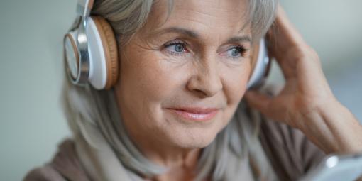 Eine ältere Frau mit Kopfhörern und Handy.