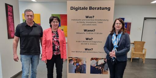 Roll-Up des Standort Trier (v.l.n.r: Michael Werhan, Dr. Yvonne Russel, Maria Dumrese) Dies steht dauerhaft in der Cafeteria des Altenheims Vereinigte Hospitien.