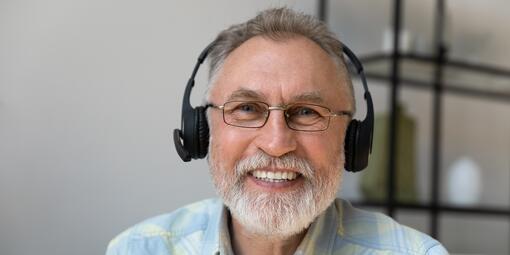 Ein Mann mit Kopfhörern lächelt in die Kamera. 