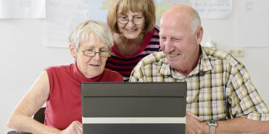 Drei Senioren schauen in einen Laptop
