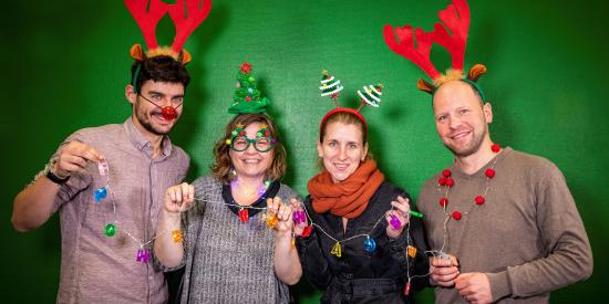 Vier Menschen lachen weihnachtsdekoriert in die Kamera