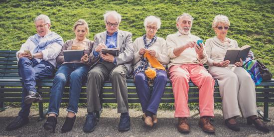 Sechs Personen mit verschiedenen Medien auf einer Bank