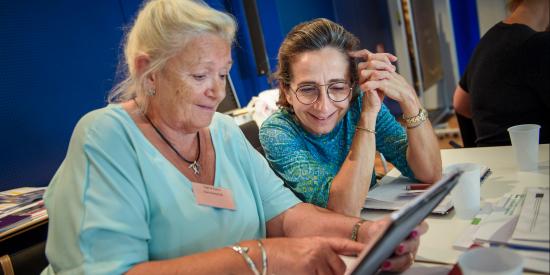Zwei Frauen sitzen an einem Tablet und lernen