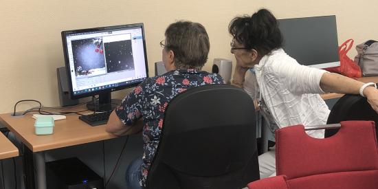 Zwei Frauen sitzen vor einem Computer.