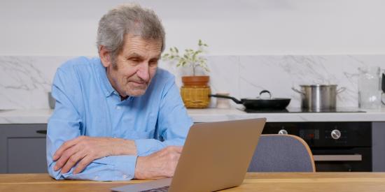 Älterer Mann sitzt am Laptop