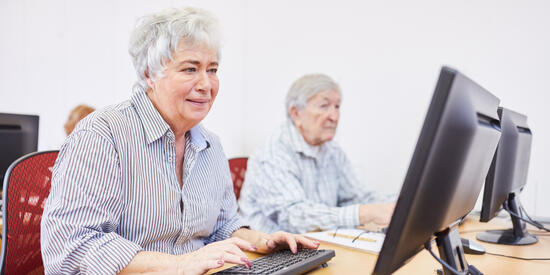 Zwei Frauen sitzen vor Computern. 