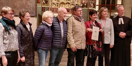 Preisverleihung in einer Kirche mit den Gewinnern, die eine Urkunde in der Hand halten