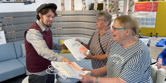 Bernd Josef Leisen überreicht zwei Besucherinnen die Lern-Tüte.