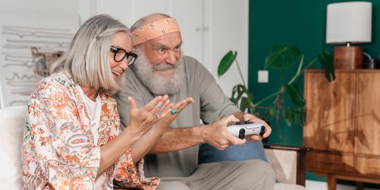 Zwei ältere Personen spielen Videospiele.