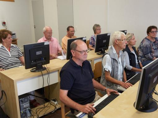 Senioren bei einem PC Kurs 60+, arbeiten an Standrechnern im Kursraum 