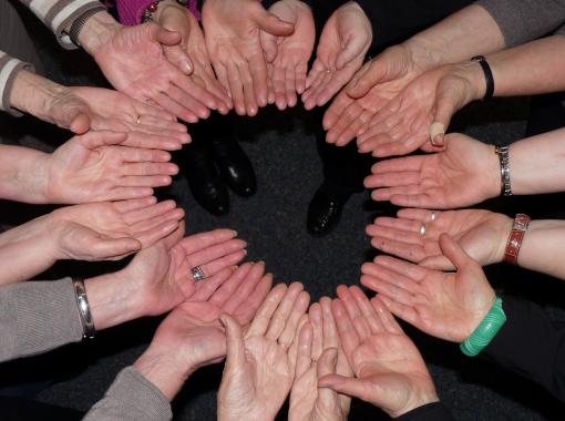 Abbildung vieler Hände, die gemeinsam einen Kreis formen als Zeichen für Zusammenhalt und Zusammenarbeit