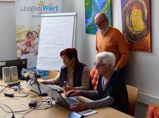 Drei Senioren an PCs im Konferenzraum