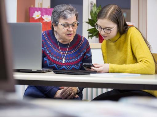 Eine Frau erklärt einer älteren Frau ein Smartphone