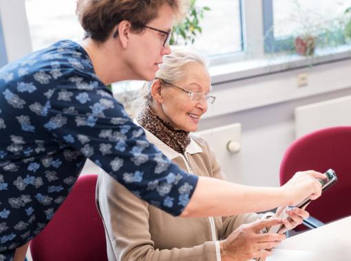 Frau erklärt älterer Frau ein Smartphone