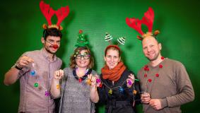 Vier Menschen lachen weihnachtsdekoriert in die Kamera