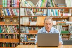 Mann mit Laptop in Bibliothek