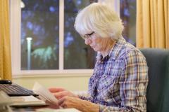 Ältere liest vor dem Laptop Rechnung