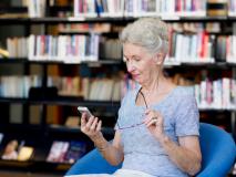 Ältere mit Smartphone in Bibliothek