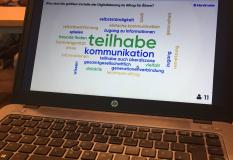 Bildschirm eines Laptops mit einer Wortwolke mit Begriffen Teilhhabe Kommunikation und mehr