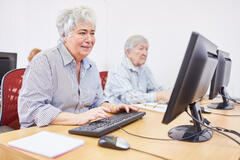 Zwei Frauen sitzen vor Computern. 