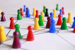 Kleine Spielfiguren in vielen verschiedenen Farben stehen auf einem Spielbrett. Das Spielbrett hat Linien, durch die die einzelnen Figuren miteinander verbunden sind.