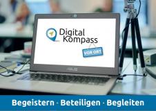 Aufgeklappter Laptop mit Digital-Kompass-Logo als Bildschirmschoner, rechts davon eine Videokamera auf einem Stativ mit dem Text: Begeistern - Beteiligen - Begleiten