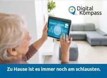 Ältere Dame im Woghnzimmer, ein Tablet in den Händen haltend, um Smart Home-Anwendungen zu steuern, mit dem Text:Zu Hause ist es immer noch am schlausten.