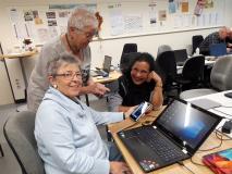 Drei Seniorinnen in einem Schulungsraum arbeiten gemeinsam am Laptop