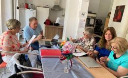 Gruppe älterer Menschen sitzt an einem runden Tisch und lernt an Laptops gemeinsam
