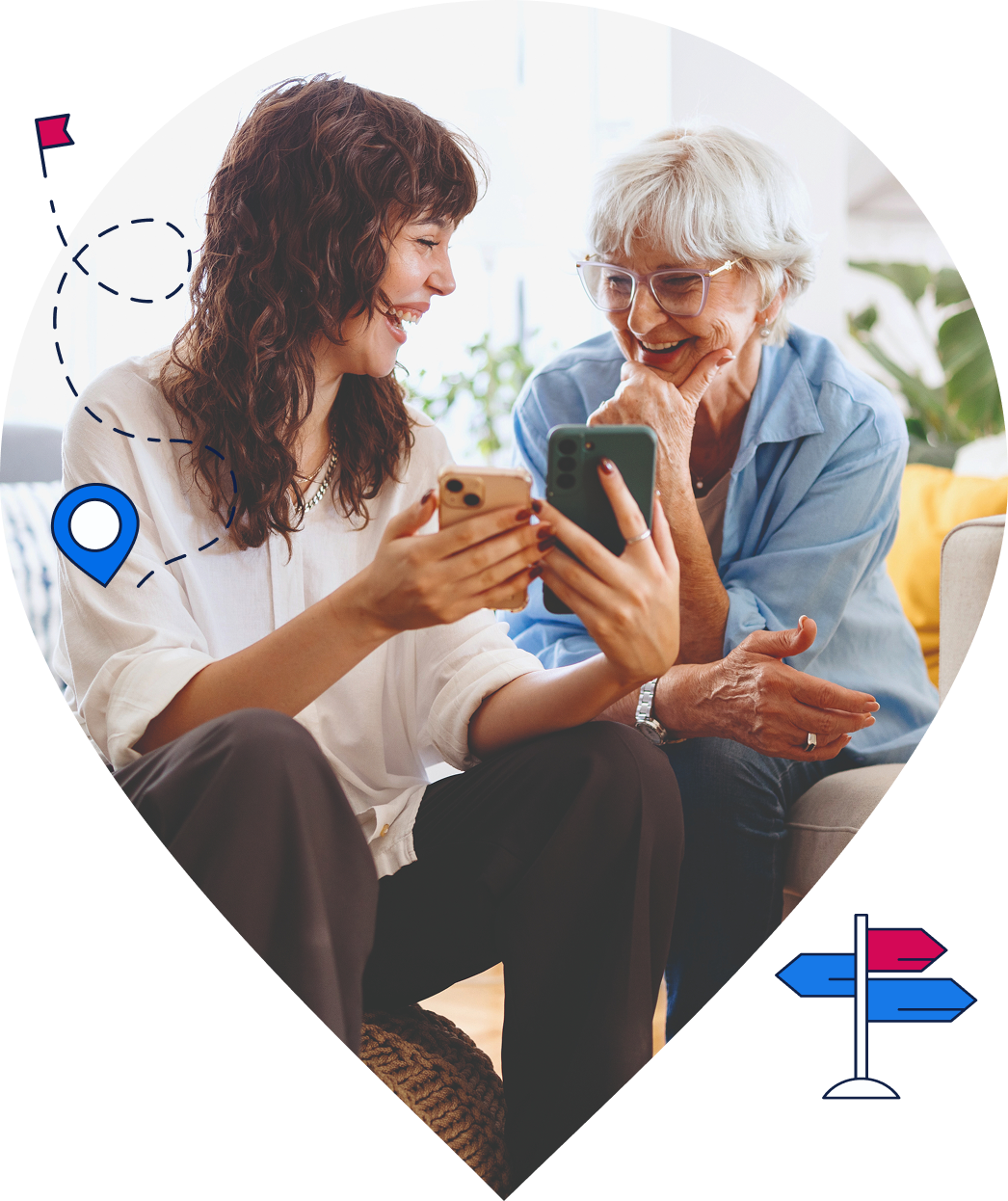 Eine jüngere und eine ältere Frau sitzen gemeinsam auf einer Couch. Die jüngere Frau zeigt der älteren Frau etwas auf zwei Handy-Bildschirmen, beide lächeln.