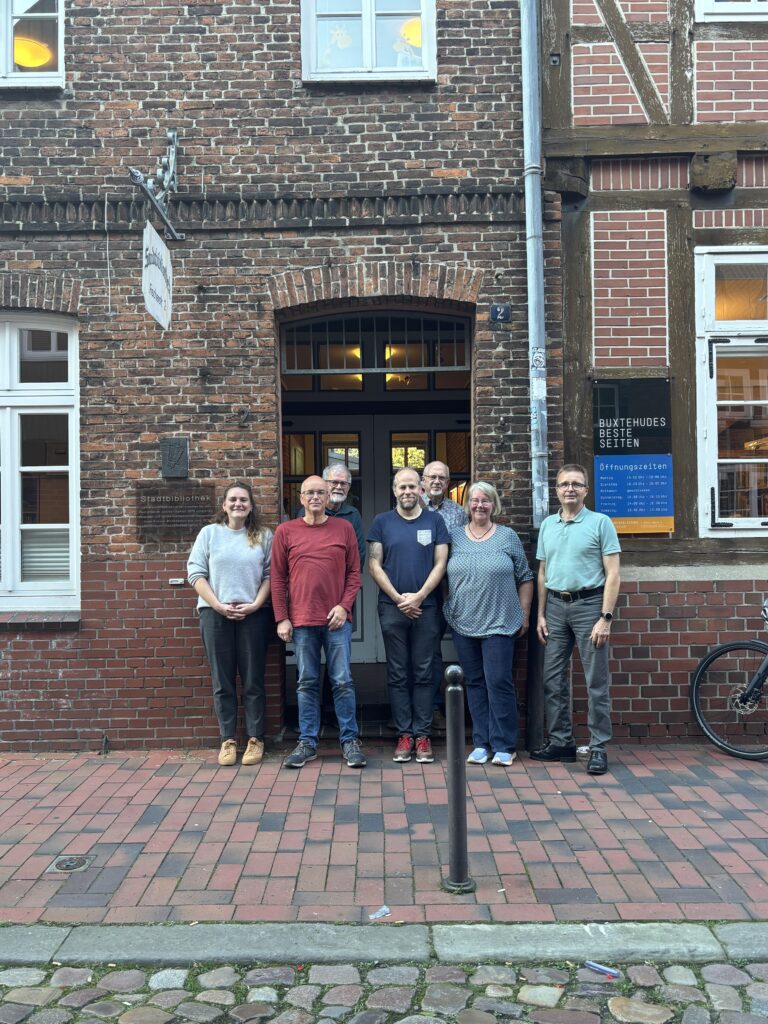 Ein Teil des Teams des Digital-Kompass Standorts Buxtehude steht vor der Bibliothek.